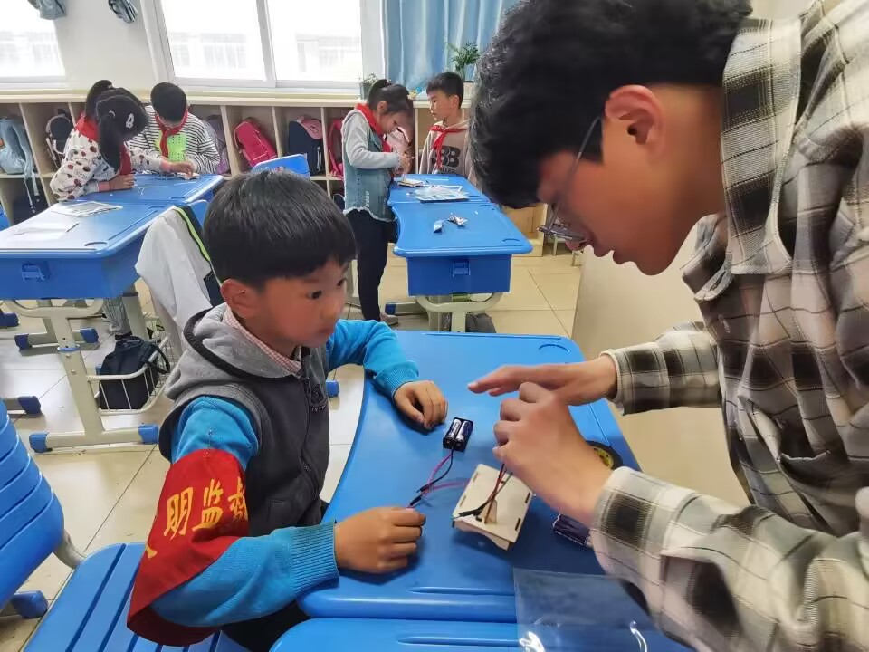 图为江苏科技大学自动化学院志愿者蔡志锦帮助润商小学二年级一班同学连接电路.jpg