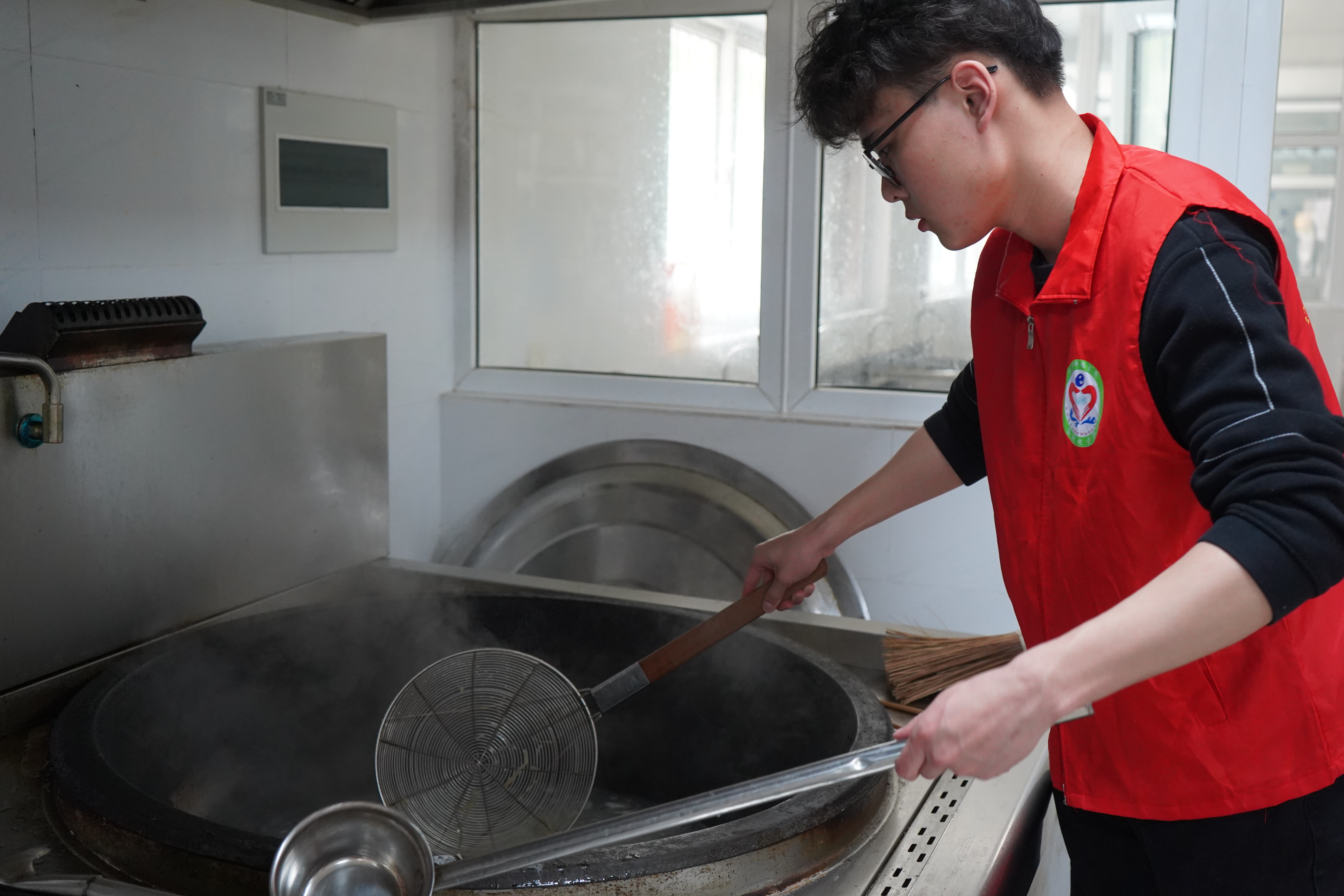 图为江苏科技大学自动化学院志愿者樊子轩为镇江市润商小学一年级一班同学准备材料，煮开面条.JPG